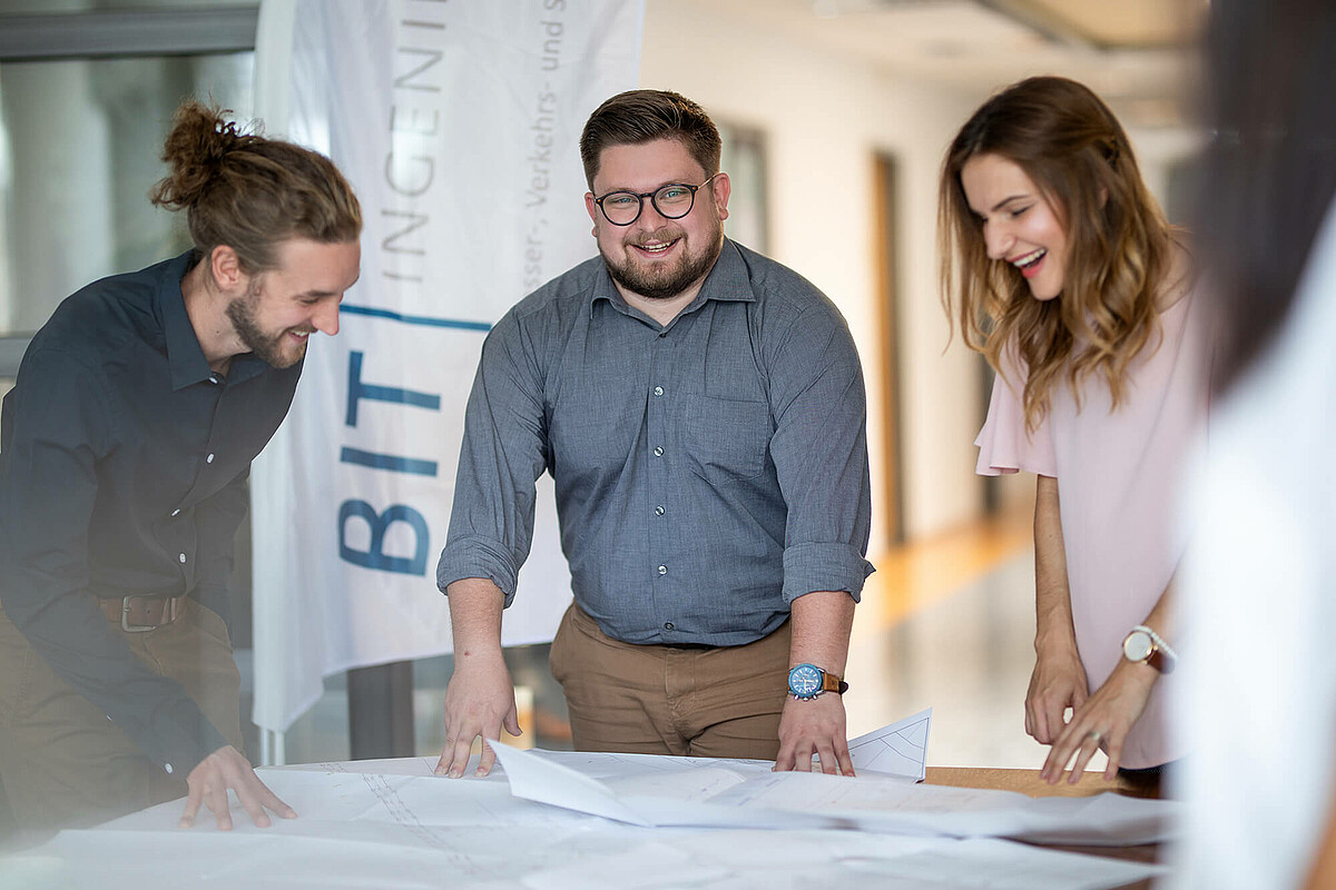 Ein Team in der BIT Zentrale Karlsruhe Kolleg:innnen aus der BIT Zentrale Karlsruhe stehen um einen Tisch.